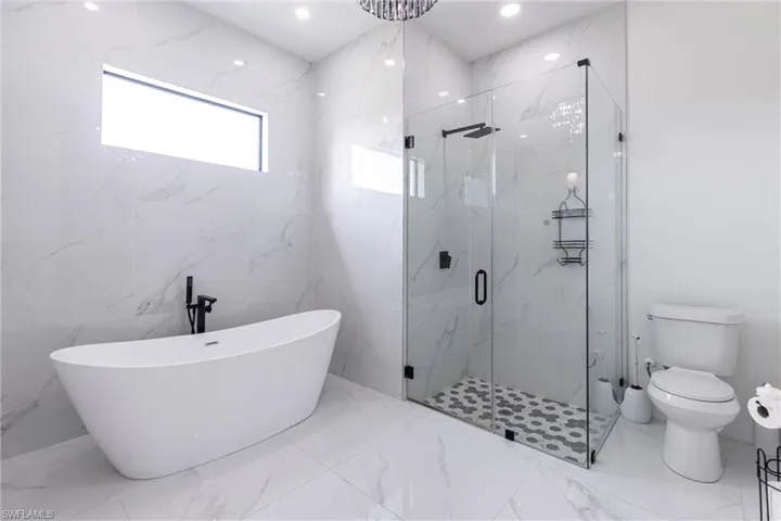 Bathroom with  tiled floors, a marble finish shower, a soaking tub, and recessed lighting