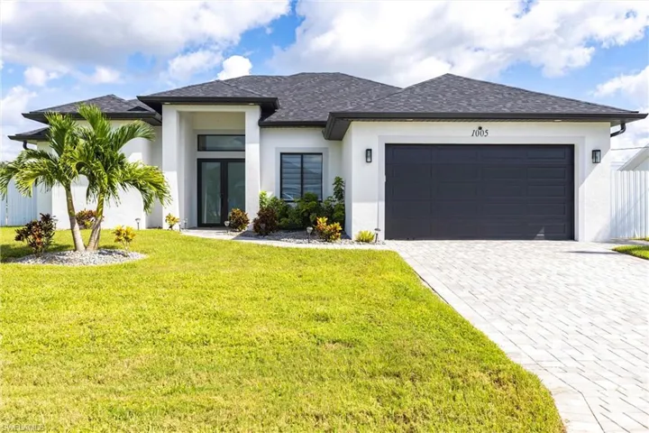 Front view of Modern style house featuring stucco siding, a front yard, a garage, decorative driveway, and roof with shingles
