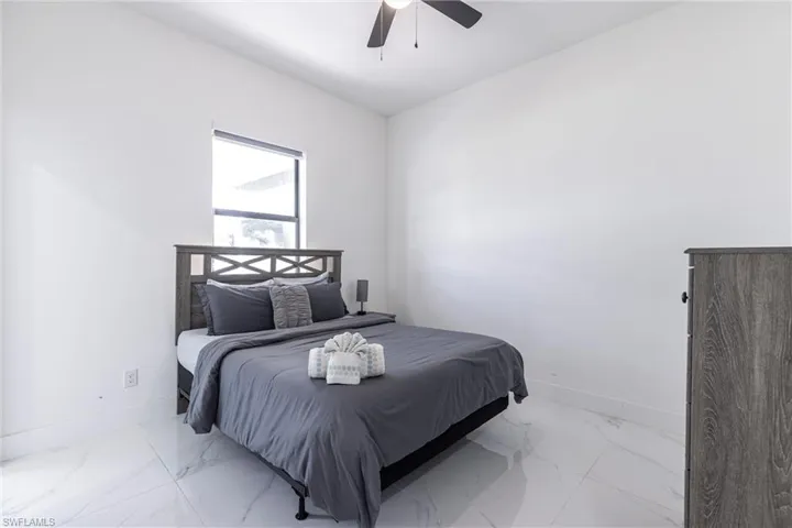 Bedroom featuring marble look tiles and a ceiling fan