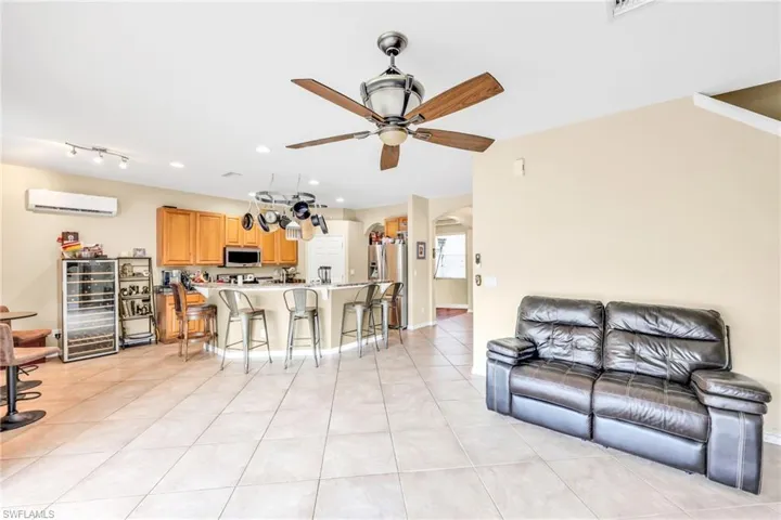 Living room featuring arched walkways, light tile patterned flooring, recessed lighting, beverage cooler, and a ceiling fan