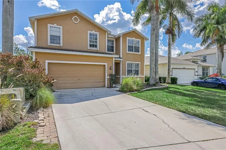 Traditional-style home with stucco siding, concrete driveway, an attached garage, and a front lawn