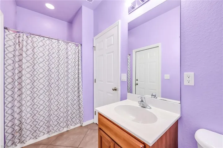 Full bath on main floor featuring vanity, a shower with shower curtain, light tile patterned floors, and a textured wall
