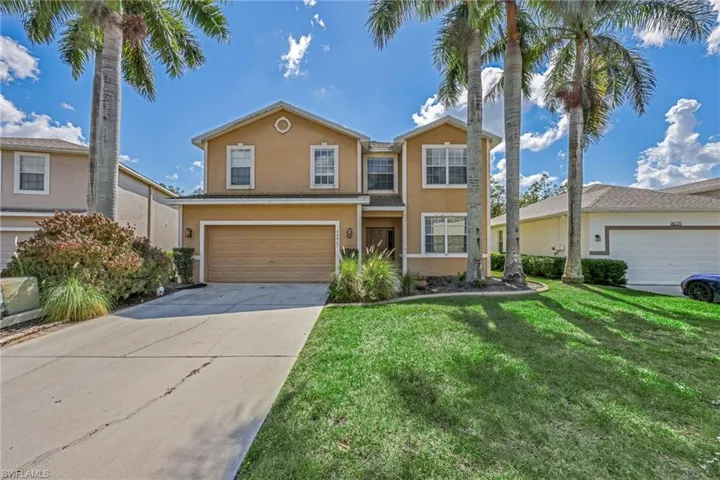 Traditional-style home with a front lawn, concrete driveway, stucco siding, and a garage