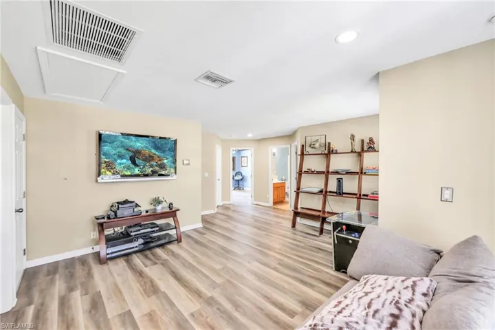 Living area with attic access, light wood-style floors, and recessed lighting