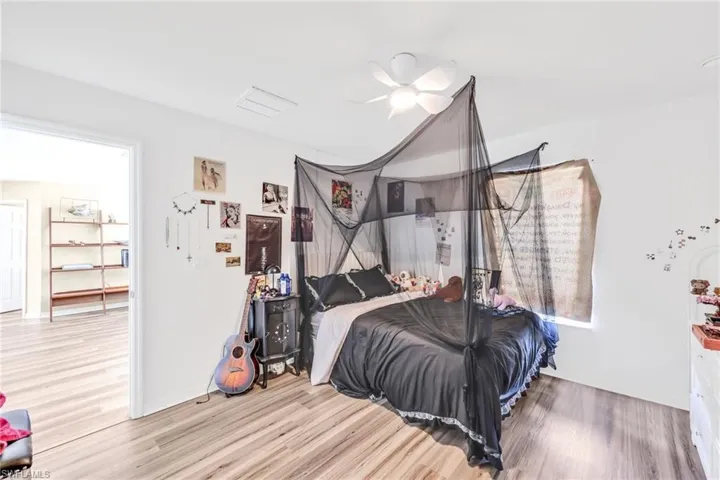 Bedroom with wood finished floors, ceiling fan, and lofted ceiling