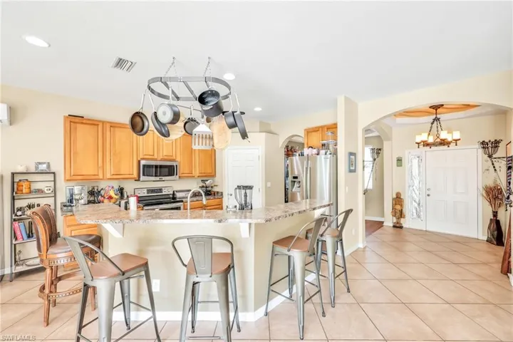 Kitchen featuring light tile patterned floors, arched walkways, a kitchen breakfast bar, stainless steel appliances, and a chandelier