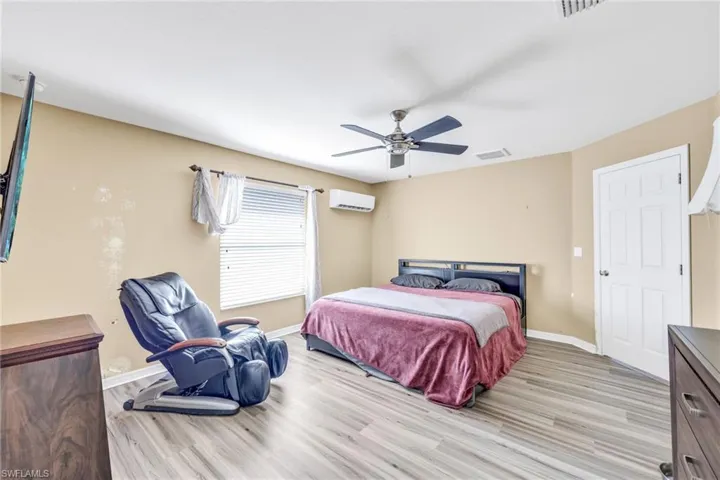 Bedroom with light wood-type flooring, a ceiling fan, and a wall unit AC