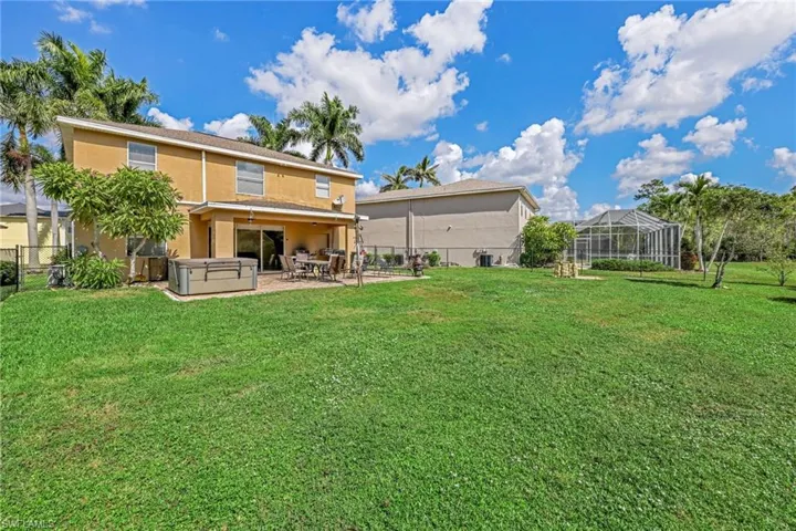 Rear view of house with a hot tub, stucco siding, a patio area, a fenced backyard, and a sunroom