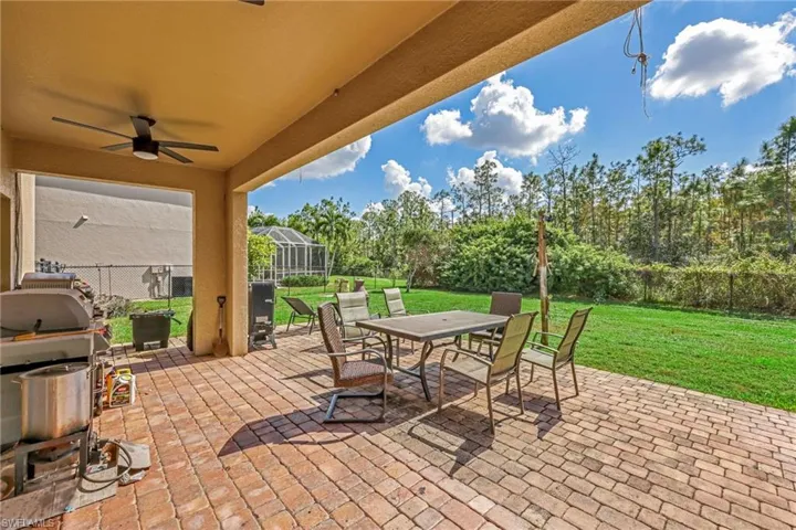 Fenced backyard featuring a patio area, outdoor dining space, a lanai, and a ceiling fan