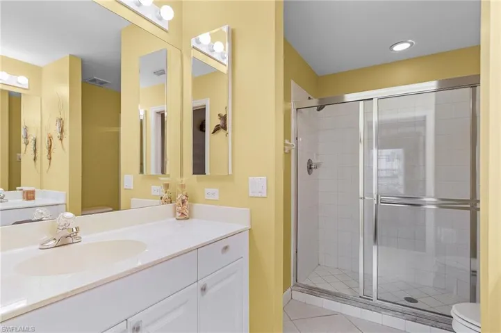 Bathroom featuring tile patterned floors, a shower with shower door, toilet, and vanity