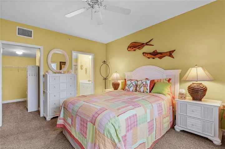 Carpeted bedroom featuring connected bathroom, a walk in closet, ceiling fan, and a closet