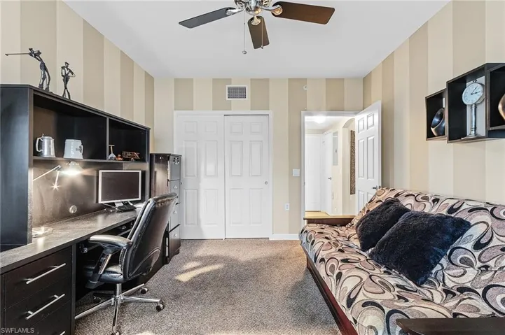 Home office with ceiling fan and carpet floors
