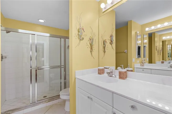 Bathroom with vanity, toilet, an enclosed shower, and tile patterned floors