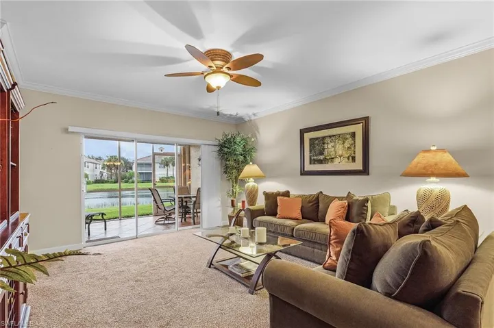 Living room featuring a water view, ceiling fan, ornamental molding, and carpet floors