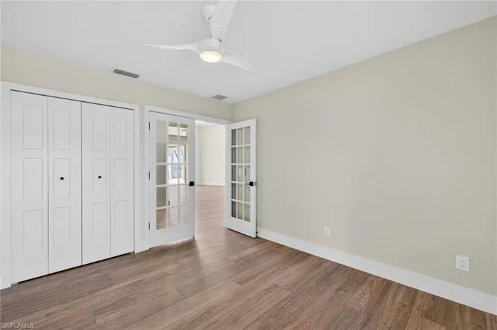 Unfurnished bedroom featuring french doors, wood finished floors, a ceiling fan, and a closet