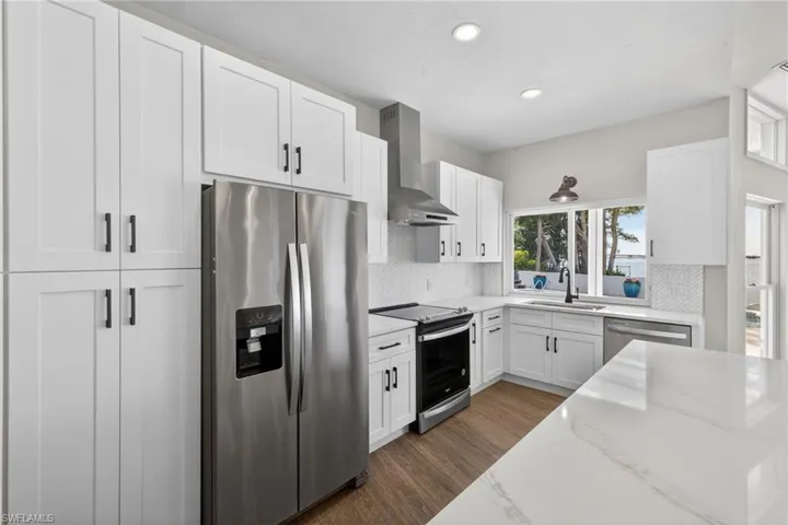 Kitchen featuring stainless steel appliances, white cabinets, dark wood-type flooring, decorative backsplash, and recessed lighting