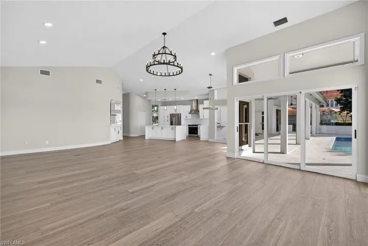 Unfurnished living room with suspended lighting, vaulted ceiling, and light wood-style flooring