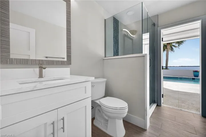 Full bath featuring a stall shower, vanity, dark wood-style flooring, and a water view