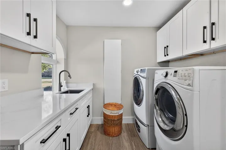 Laundry room with cabinet space, washer and dryer, dark wood finished floors, and recessed lighting