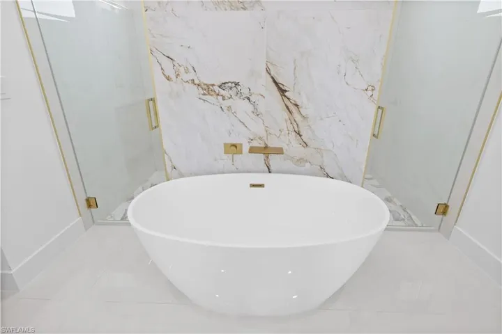 Bathroom with tile floors, separate shower and tub, and tile walls
