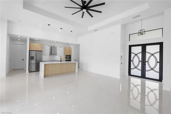 Kitchen with stainless steel appliances, an island with sink, a raised ceiling, and pendant lighting