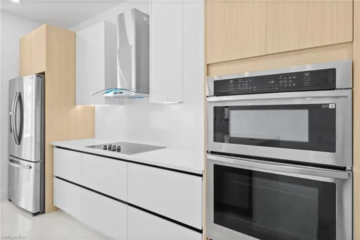 Kitchen with stainless steel appliances, wall chimney exhaust hood, and light brown cabinets