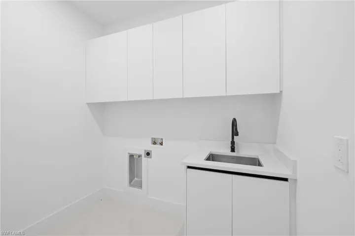 Laundry area with sink, hookup for an electric dryer, washer hookup, and cabinets