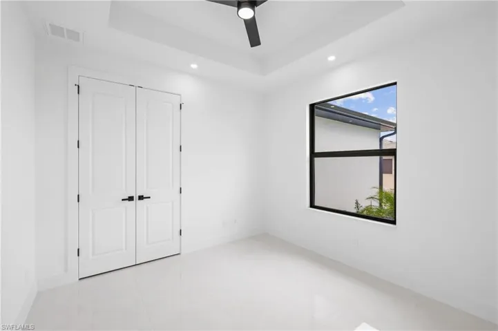Tiled spare room with a tray ceiling and ceiling fan