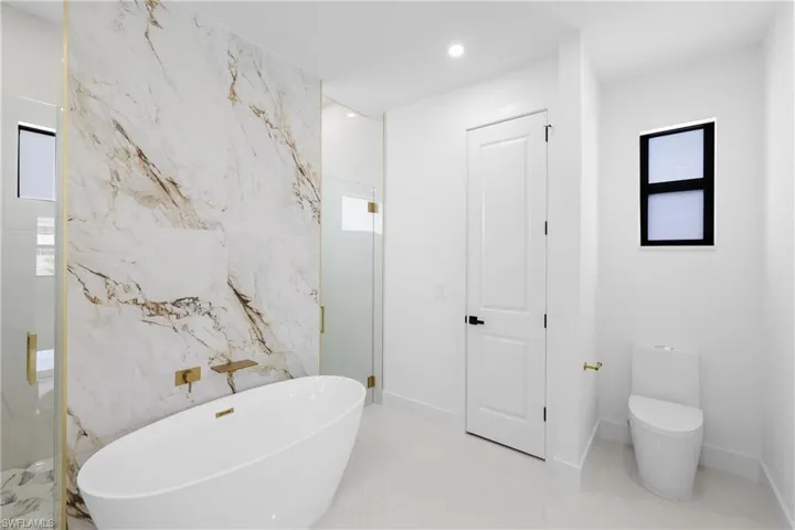 Bathroom featuring toilet, tile floors, and plus walk in shower