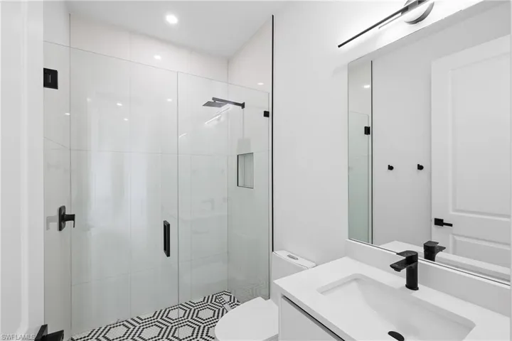 Bathroom featuring a shower with door, toilet, and vanity