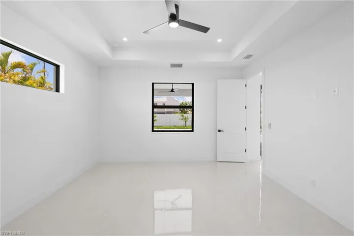 Tiled spare room with ceiling fan and a tray ceiling