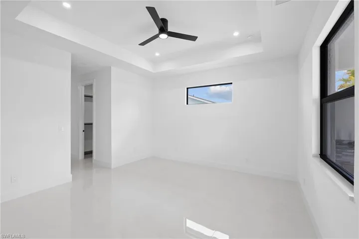 Unfurnished room featuring ceiling fan, a tray ceiling, and concrete flooring