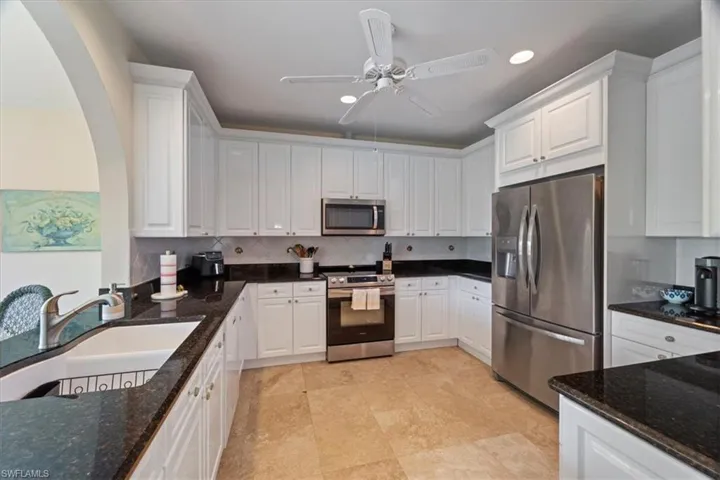 Kitchen featuring stainless steel appliances, dark stone countertops, white cabinets, backsplash, and recessed lighting