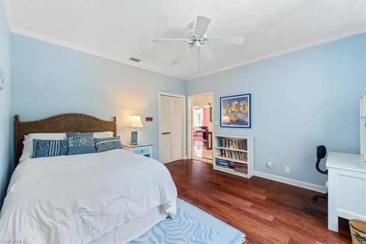 Bedroom with ornamental molding, a closet, dark wood-type flooring, and ceiling fan