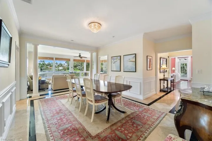 Dining area with decorative columns, a decorative wall, a wainscoted wall, ornamental molding, and plenty of natural light
