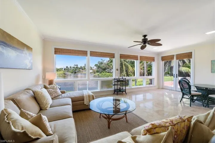 Living room with ornamental molding, ceiling fan, and a water view