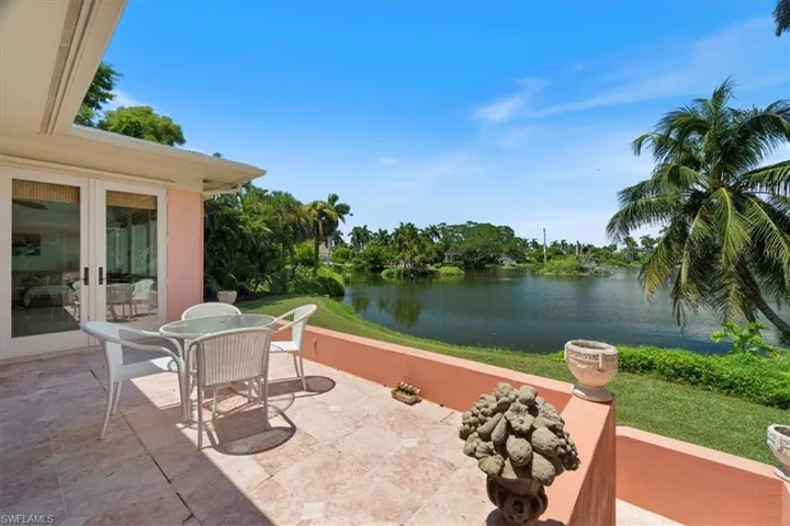 View of patio with a water view, outdoor dining area, and view of wooded area
