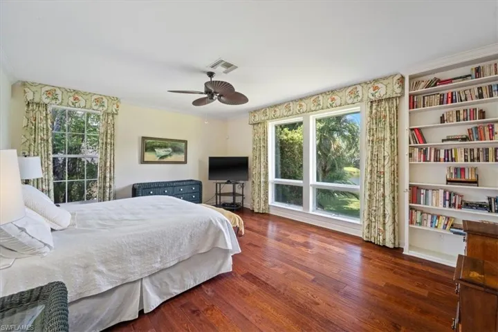 Bedroom featuring hardwood / wood-style floors, crown molding, and a ceiling fan