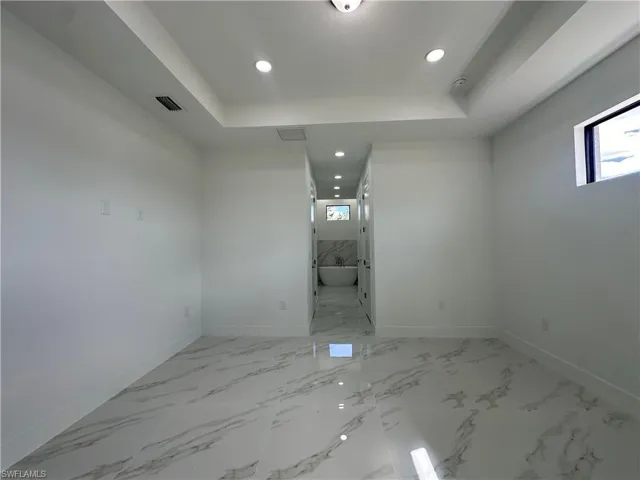 Tiled spare room with a raised ceiling and a wealth of natural light