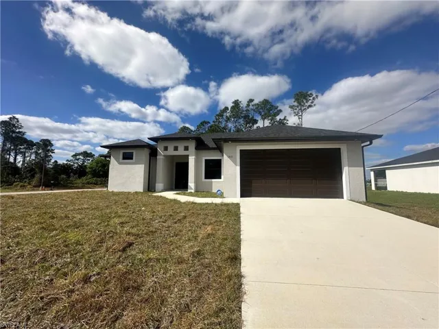 View of front facade featuring a garage and a front lawn