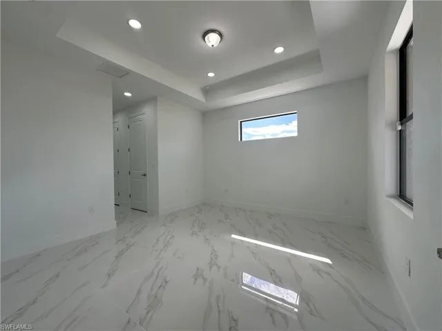 Tiled spare room featuring a raised ceiling