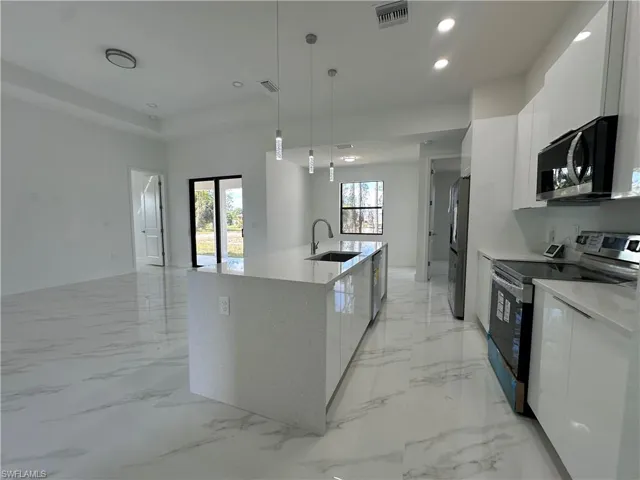 Kitchen featuring appliances with stainless steel finishes, white cabinetry, plenty of natural light, and light tile floors