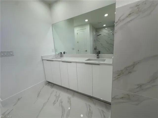 Bathroom featuring walk in shower, tile flooring, and double vanity