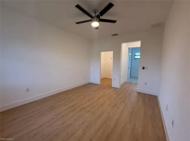 Unfurnished bedroom with light wood-style floors, ceiling fan, and a walk in closet