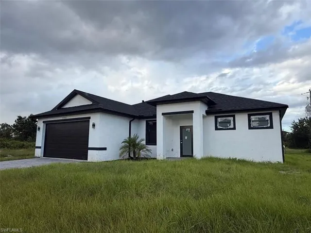 View of front facade featuring stucco siding, a garage, driveway, and a front lawn