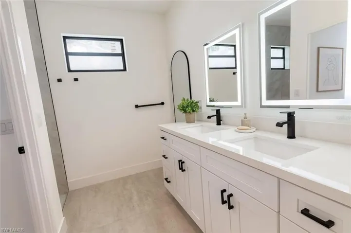 Full bath with double vanity and baseboards