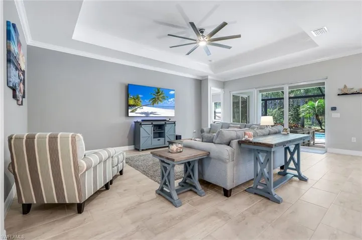 Living area featuring a raised ceiling, crown molding, a ceiling fan, and light wood-type flooring