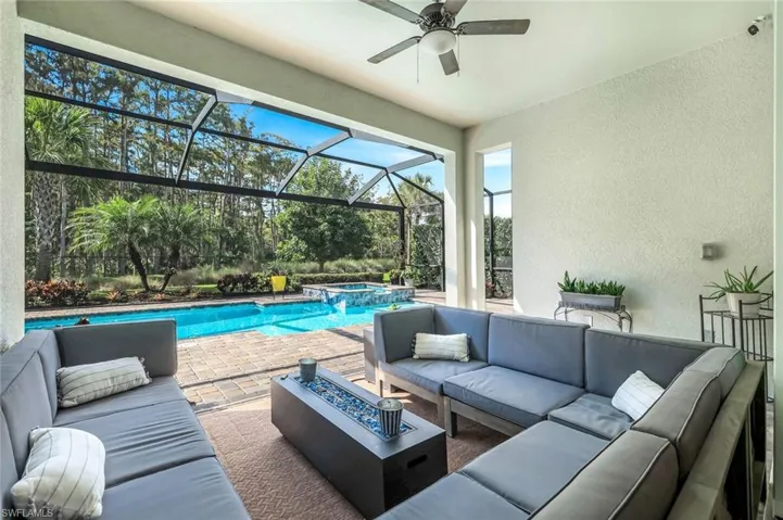View of patio / terrace featuring outdoor lounge area, a pool with connected hot tub, glass enclosure, and a ceiling fan
