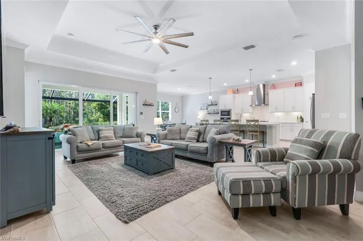 Living area with ornamental molding, a raised ceiling, ceiling fan, and recessed lighting