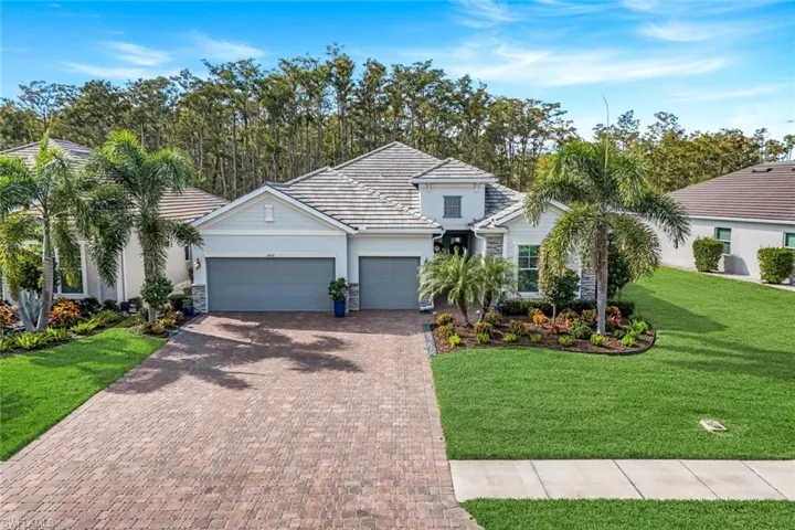 View of front of property with an attached garage, a front lawn, decorative driveway, and a tile roof